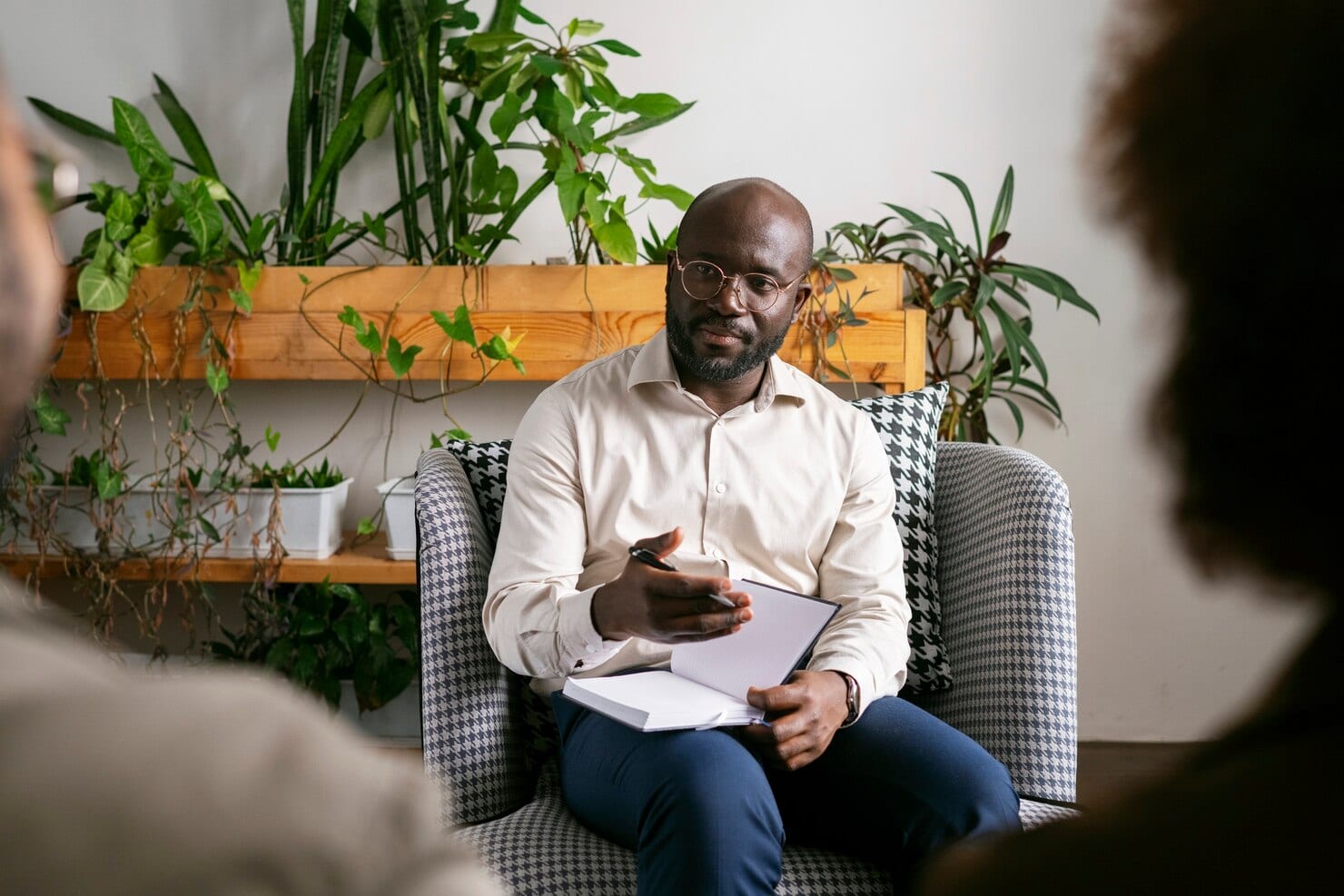 A psychologist listening and taking notes while a client speaks in a therapy session